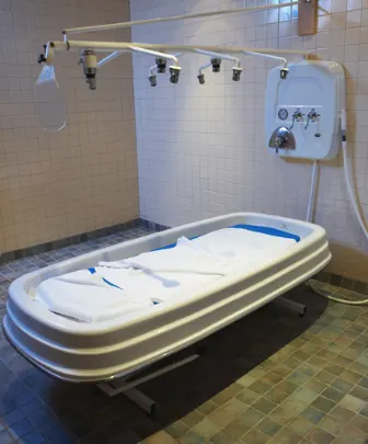 Private hydrotherapy treatment room with a tiled interior and prepared treatment table